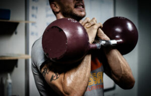 Man working out by lifting two kettle bells