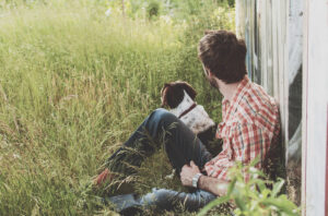 Man sitting with a dog in a field